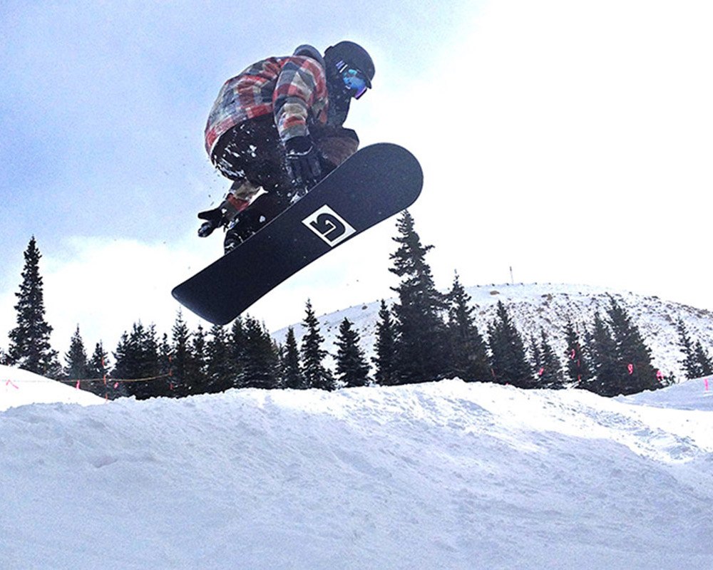 Denver wedding photographer Robby Holmes jumping through the air on a snowboard.