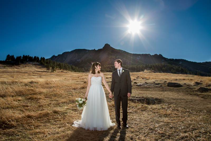 A bride and groom stand in front of the mountains at their modern Boulder, Colorado wedding.