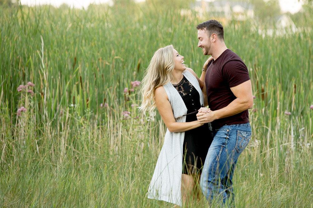A couple dancing in field of tall grass during their romantic outdoor engagement photo session in Fort Collins.