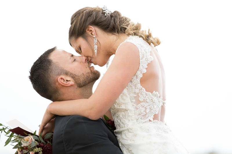 A stylish bride and groom share a kiss in a field near their modern Denver, Colorado wedding.