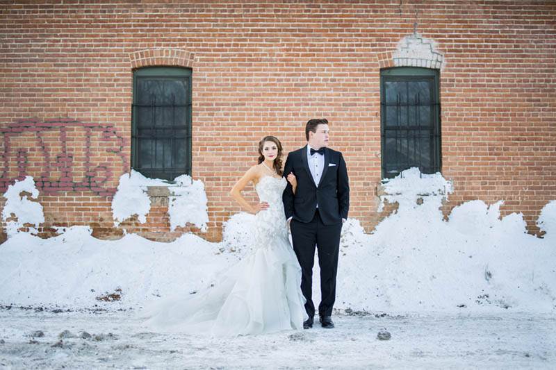 A modern colorado couple stand in front of a rustic brick wall at their old town fort collins winter wedding.